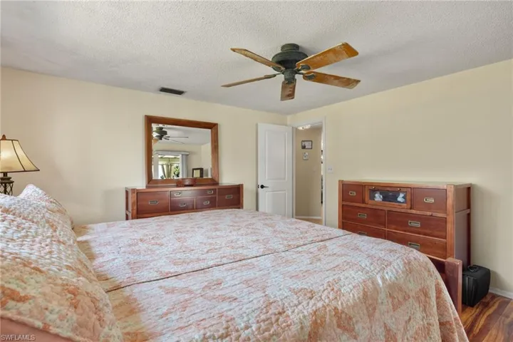 Primary Bedroom featuring a textured ceiling, wood-type flooring, and ceiling fan