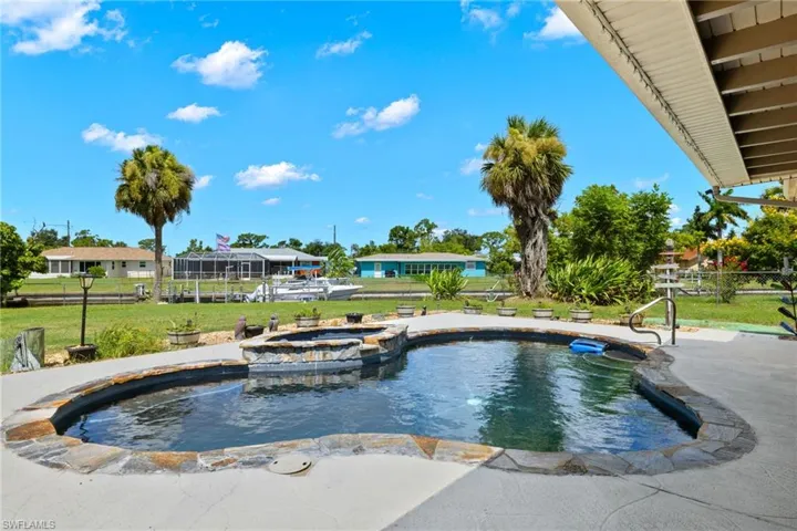 View of swimming pool with a lawn and an in ground hot tub