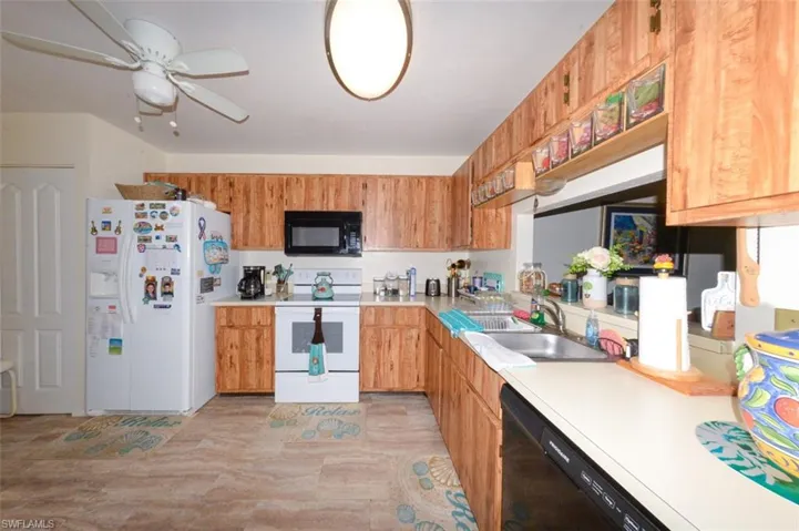 Kitchen with black appliances, light countertops, and a ceiling fan