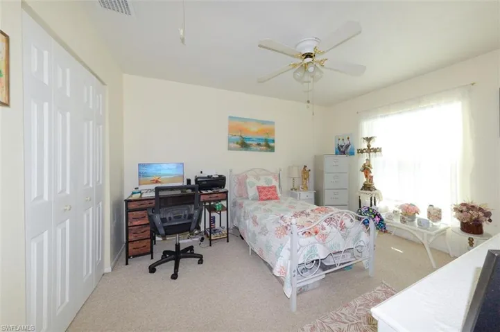 Bedroom featuring a closet, an office area, light colored carpet, and ceiling fan