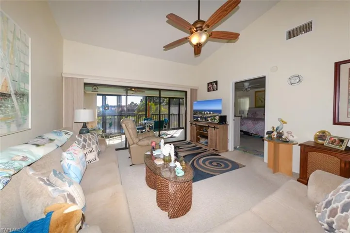 Living area with vaulted ceiling, light carpet, and ceiling fan