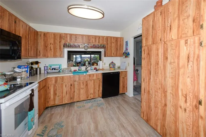 Kitchen with black appliances, light countertops, light wood-type flooring, and wood finish cabinets