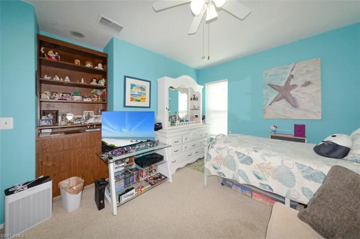 Bedroom featuring light carpet, a ceiling fan, and heating unit