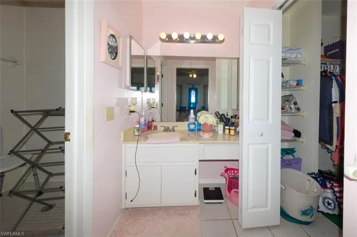 Ensuite bathroom featuring vanity, light tile patterned flooring, and a walk in closet