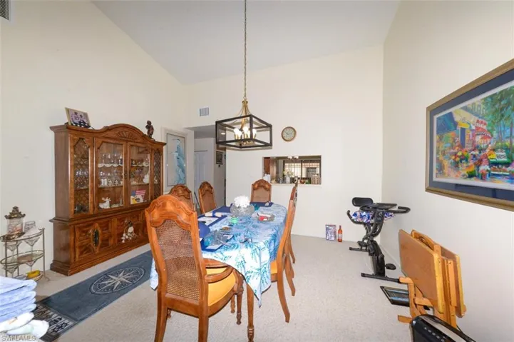 Dining area with carpet, vaulted ceiling, and a chandelier