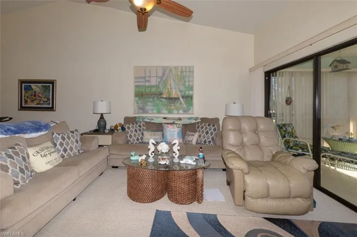 Carpeted living room with ceiling fan and lofted ceiling