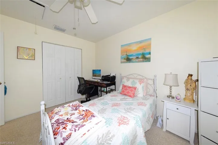 Bedroom with light carpet, ceiling fan, and a closet