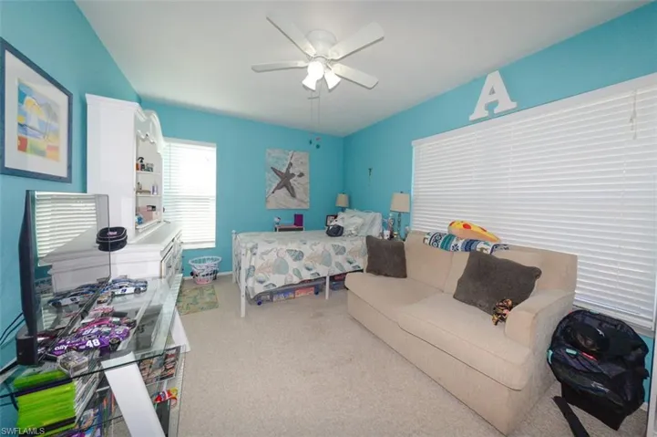 Carpeted bedroom with a ceiling fan