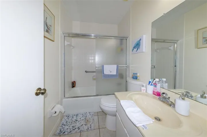 Full bathroom with vanity, enclosed tub / shower combo, and light tile patterned floors