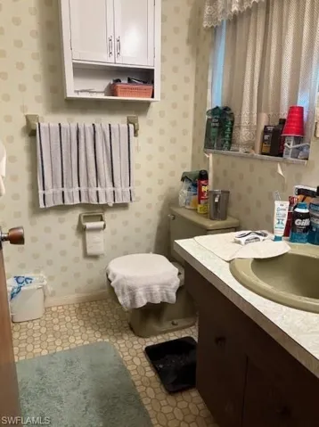 Main bathroom with vanity and wallpapered walls