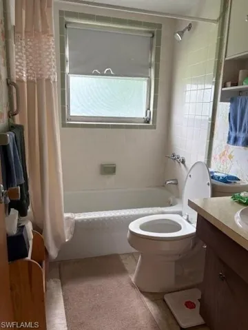 Bathroom featuring shower / bathtub combination with curtain and vanity