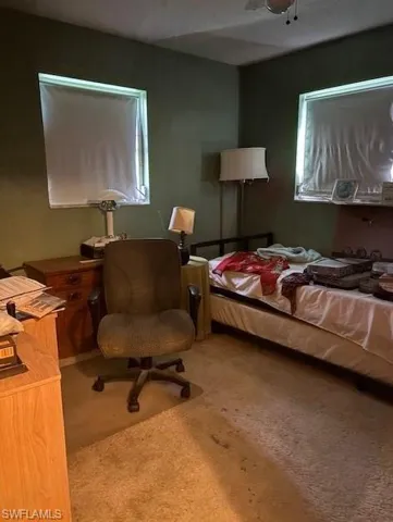 Bedroom featuring light colored carpet and a desk