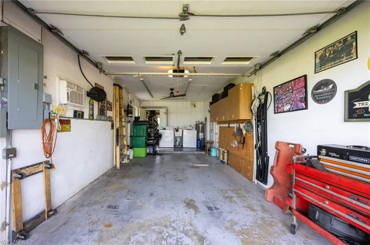 Garage featuring electric panel, washer and clothes dryer, a garage door opener, water heater, and a wall mounted AC