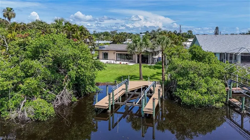 Dock area with boat lift, a water view, and a yard