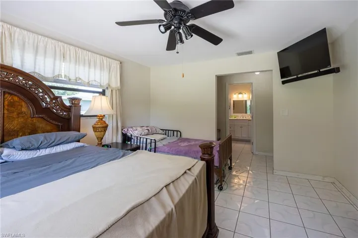 Bedroom with light marble finish floors, a ceiling fan, and connected bathroom