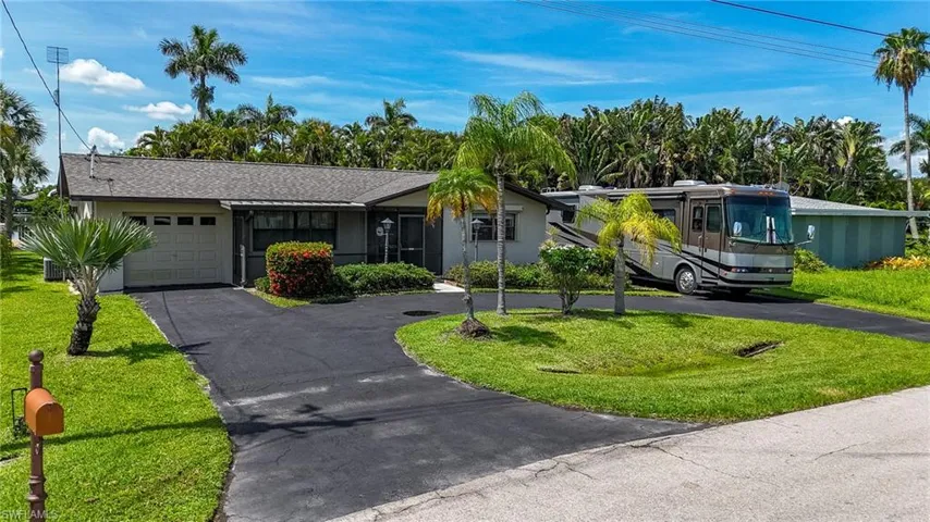 Single story home featuring an attached garage, asphalt driveway, and a front lawn