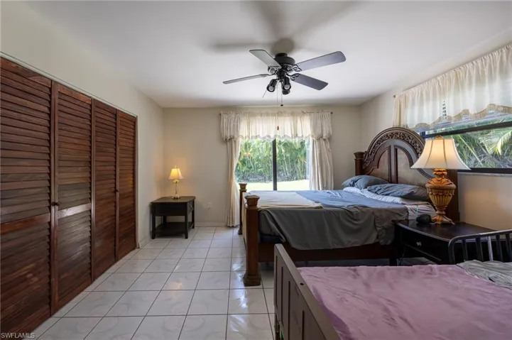 Bedroom with a closet, ceiling fan, and light marble finish floors
