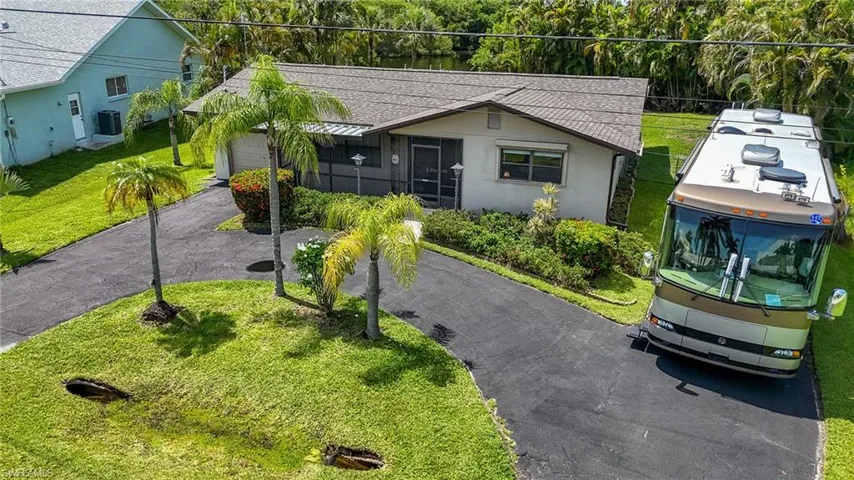 View of front of property featuring driveway, a shingled roof, a front yard, and a garage