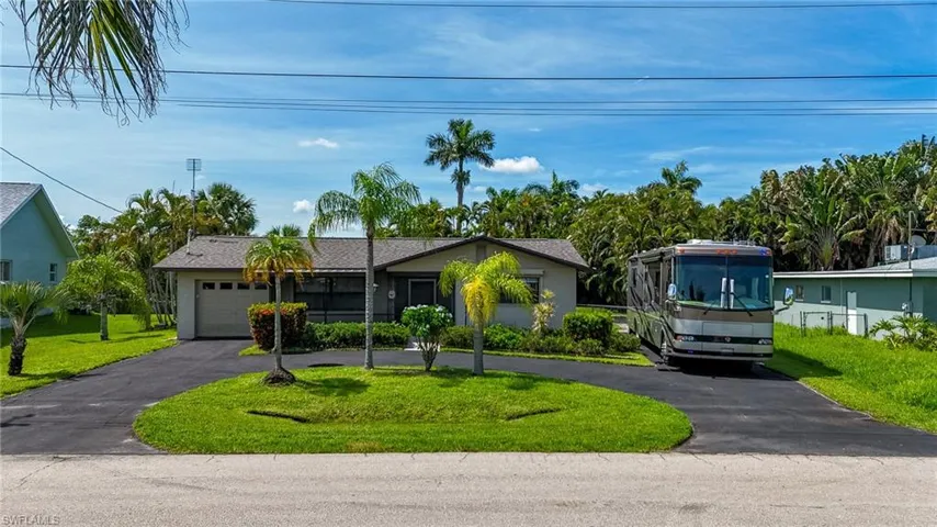 View of front of home with curved driveway, a front lawn, and a garage