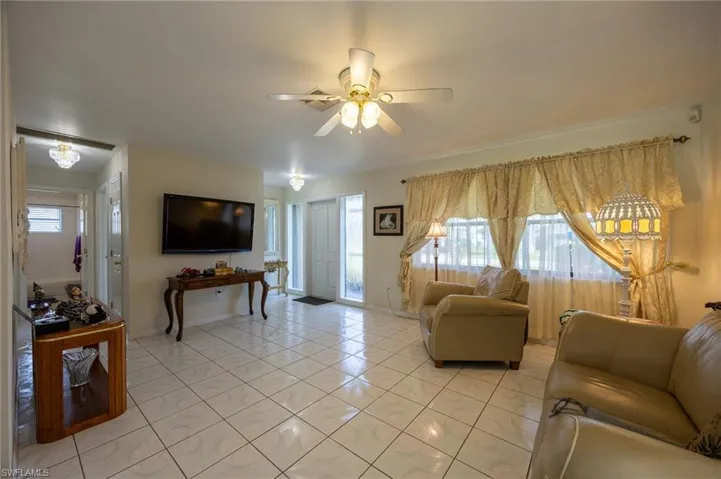 Living area featuring a ceiling fan and light marble finish floors
