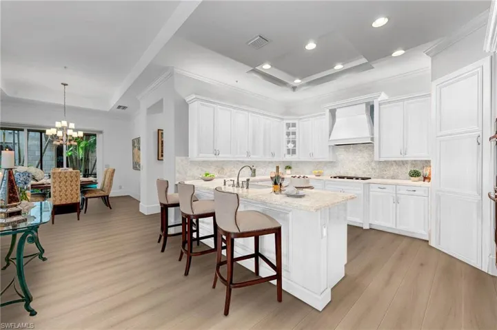 Virtually-remodeled kitchen with Taj Mahal quartzite and wide-plank wood flooring.