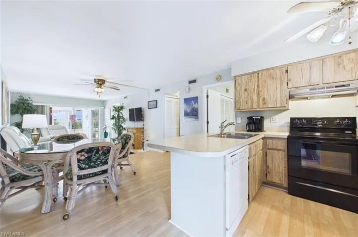 Kitchen with a ceiling fan, black range with electric stovetop, open floor plan, and light countertops