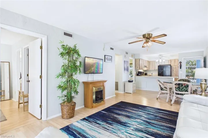 Living room with light wood-type flooring, a fireplace, and ceiling fan