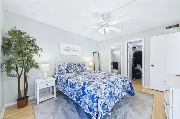 Bedroom featuring a walk in closet, light wood-type flooring, ceiling fan, and ensuite bath