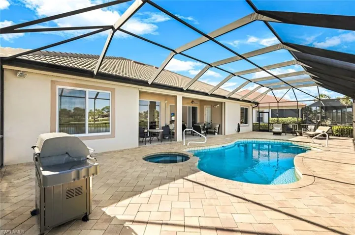 View of swimming pool with a pool with connected hot tub, ceiling fan, glass enclosure, a patio area, and area for grilling