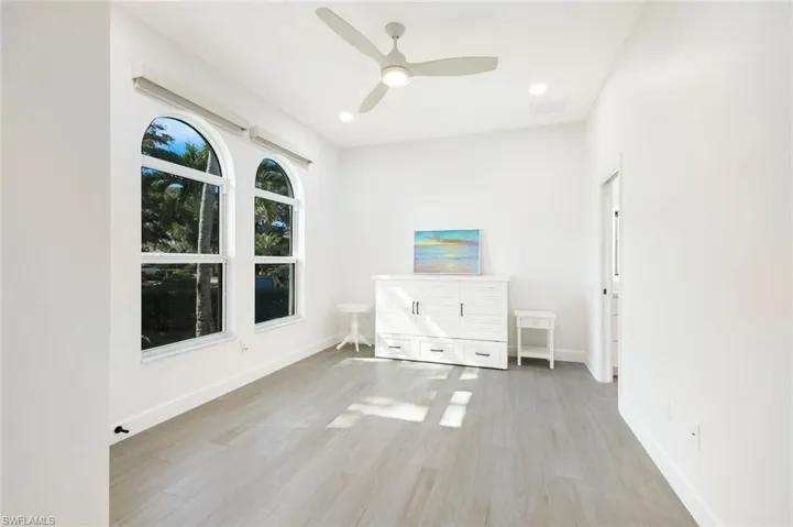 Bedroom with a ceiling fan, recessed lighting, plank tile floors, and tall baseboards