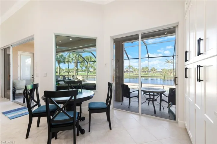 Dining area featuring light tile patterned floors, a high ceiling, a sunroom, a water view, and crown molding