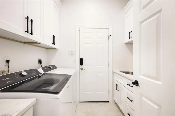 Washroom with washer and dryer, light tile patterned flooring, cabinet space, and a sink