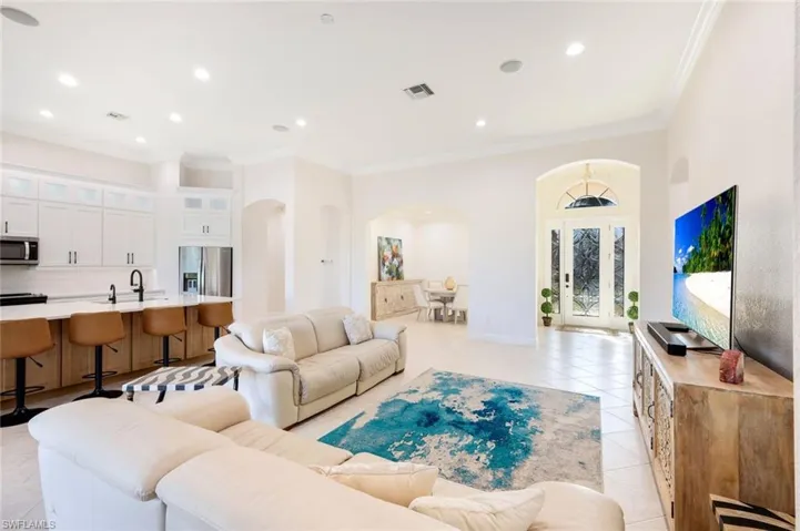 Living area featuring crown molding, light tile patterned flooring,, and arched walkways