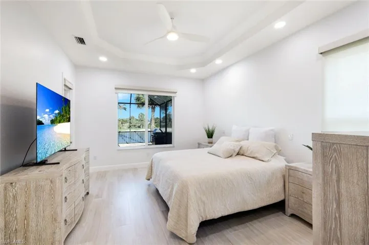 Primary Bedroom with a tray ceiling, recessed lighting, and light wood-style tile floors