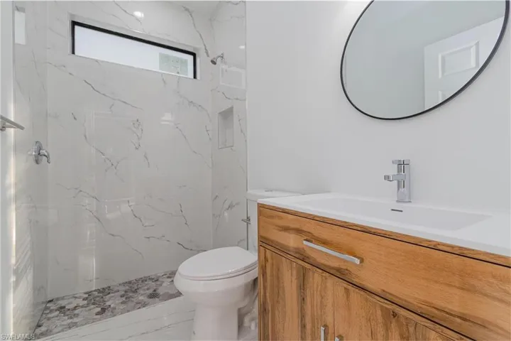 Bathroom with vanity, a tile shower, and toilet