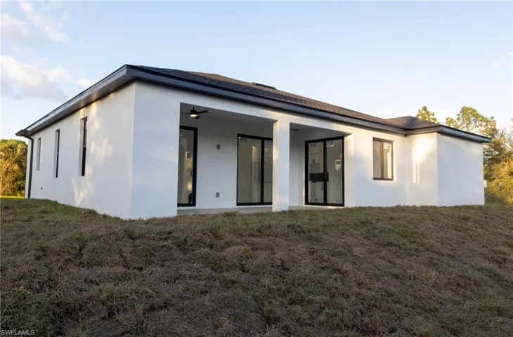 Rear view of house featuring a yard and ceiling fan