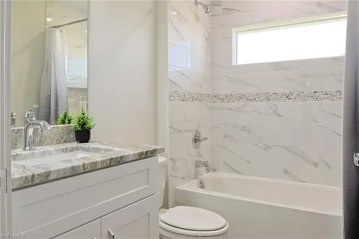 Bathroom featuring a white vanity with a light-toned stone countertop and integrated sink