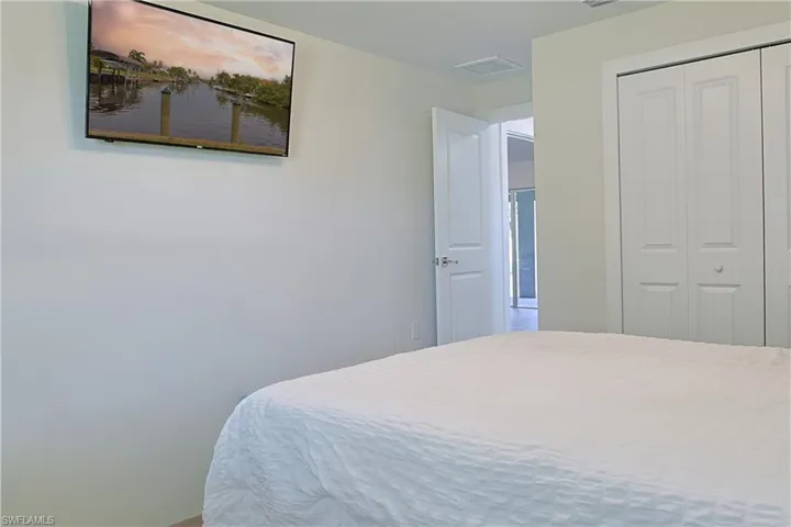 Interior room with light-toned walls, featuring a wall-mounted television, white bi-fold closet doors, and an open doorway