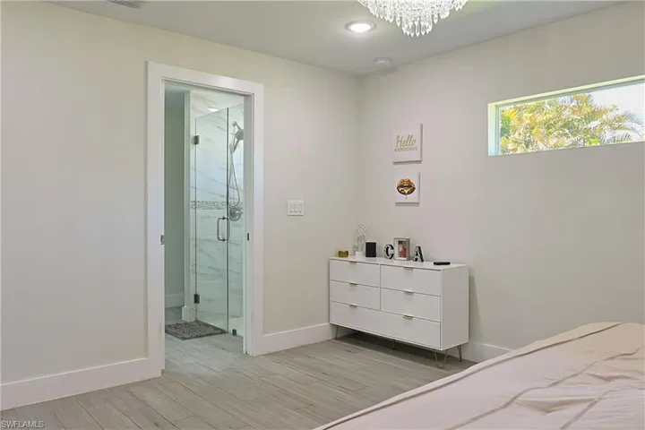 Light-toned wood-finish flooring extending from the room into a full glass-enclosed shower with tiled walls