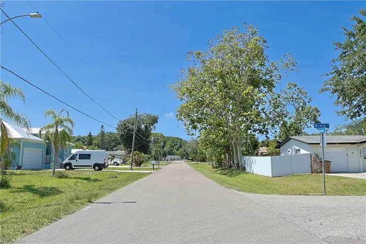 Paved street with overhead utilities, mature trees, and street signage