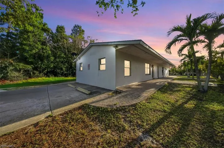 View of side of home with stucco siding and a yard