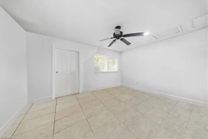 Spare room with a ceiling fan, attic access, and light tile patterned floors