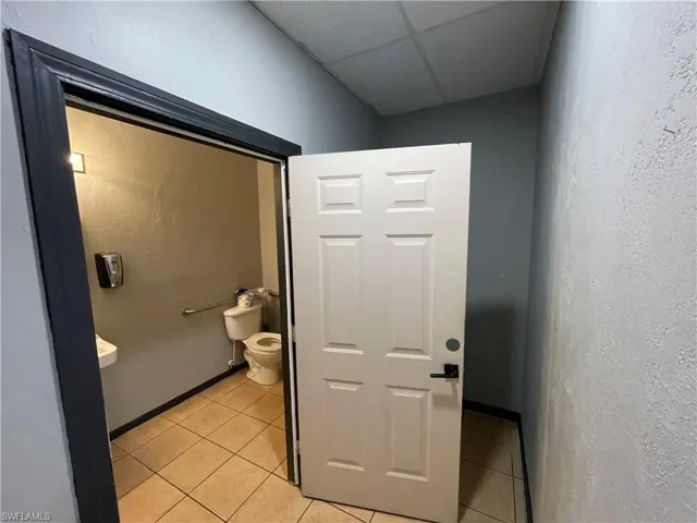 Bathroom featuring a drop ceiling, tile patterned floors, and toilet