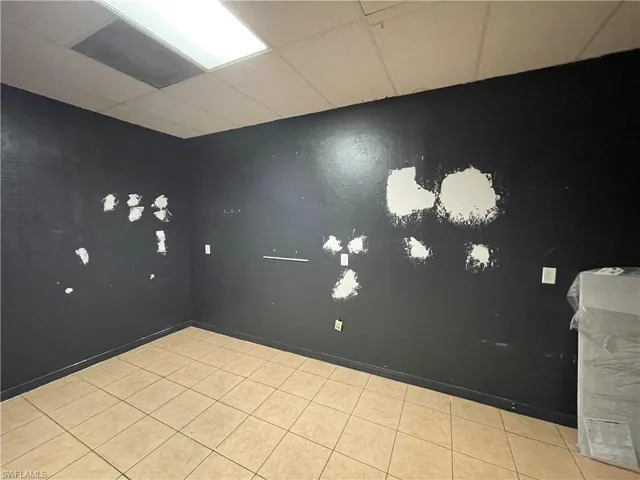 Unfurnished room with light tile patterned flooring and a drop ceiling