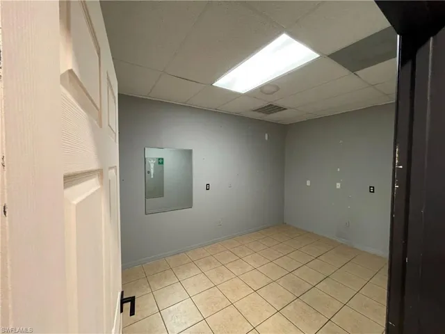Empty room with light tile patterned floors and a drop ceiling