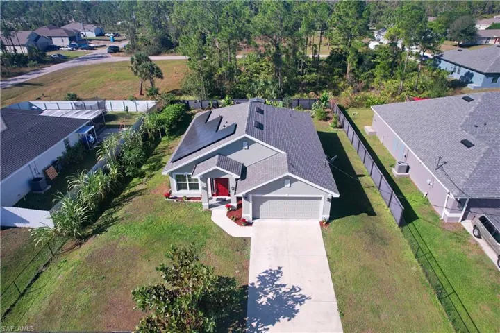 Single-story residence featuring a gray exterior, a red entry door, a shingled roof with solar panels, and an attached garage