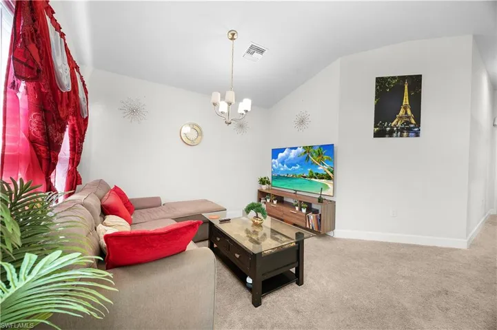 Angled ceiling, carpet flooring, and a multi-light chandelier