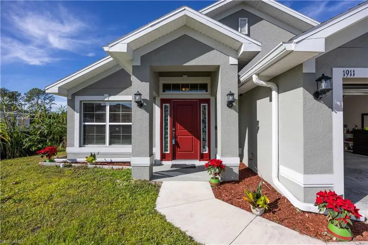 Stucco exterior with a prominent red entry door and transom window