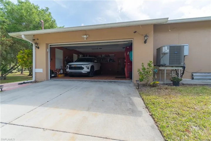 Garage with driveway and central AC unit