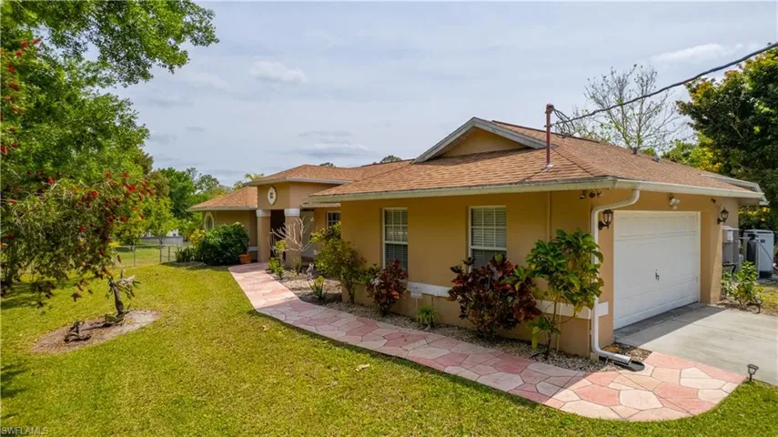View of front of home featuring driveway, fence, an attached garage, a front lawn, and stucco siding